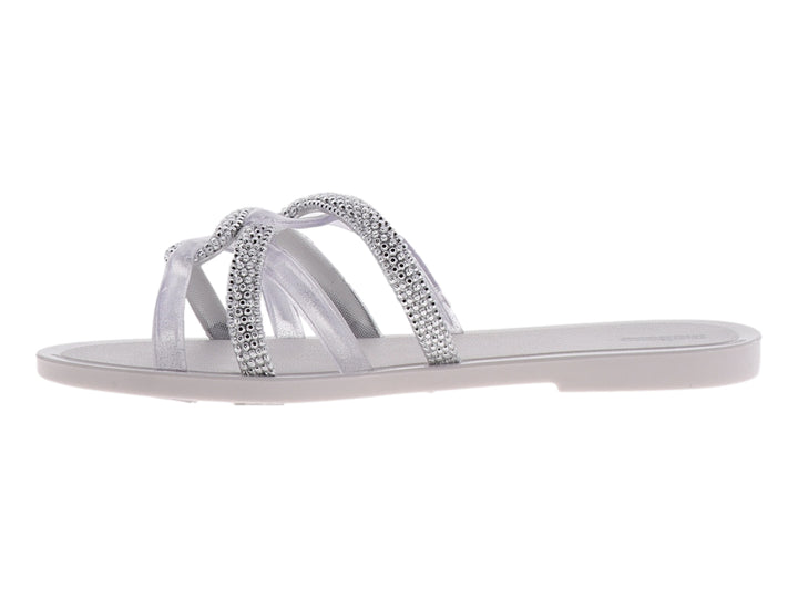 Sandalia Melissa blanca brillante con tiras cruzadas decoradas con cristales y suela plana.