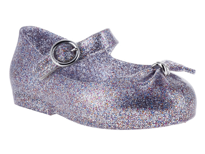 Zapato infantil color plata con acabado de glitter brillante y cierre de hebilla.