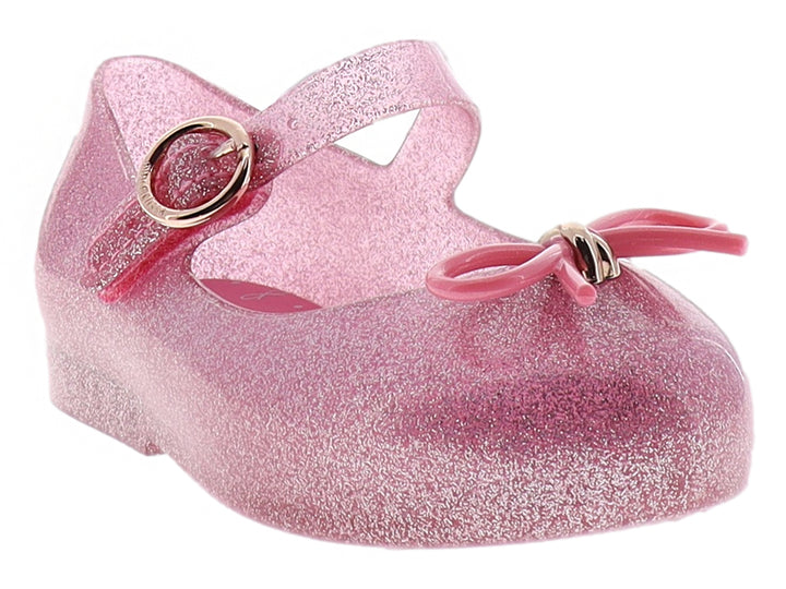 Zapato infantil Mini Melissa color rosa con glitter, moño decorativo y correa con hebilla dorada.