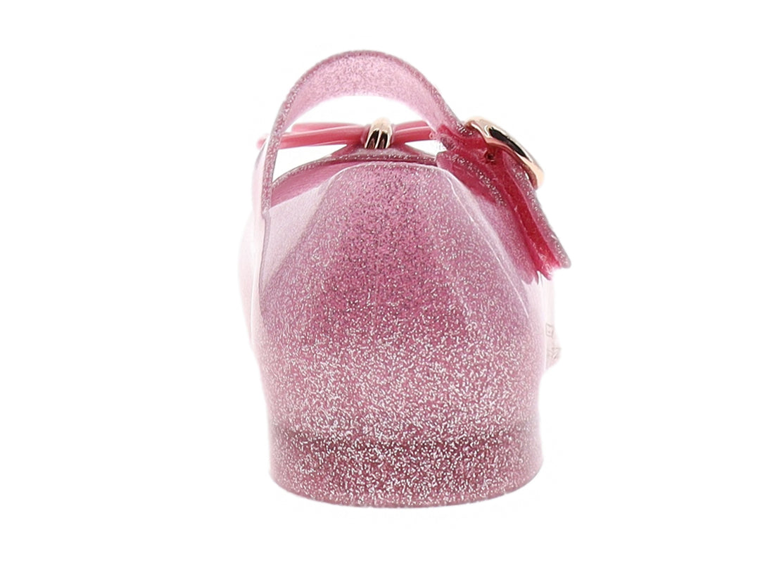 Zapato infantil Mini Melissa color rosa con glitter, moño decorativo y correa con hebilla dorada.