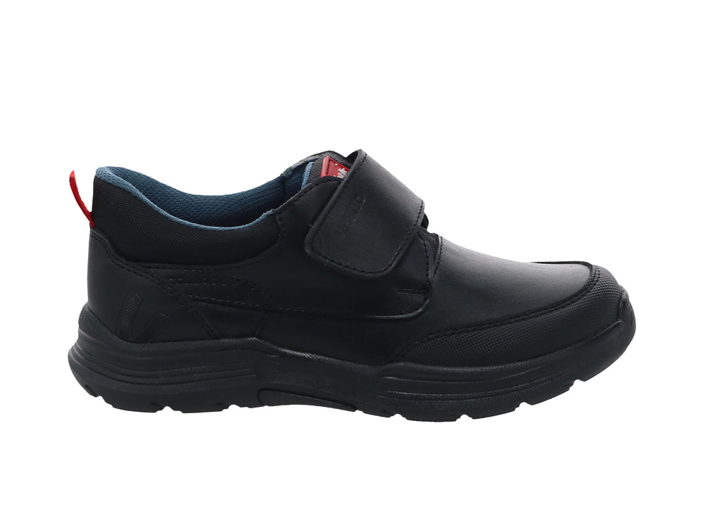 Zapato infantil negro de material sintético con cierre de velcro y detalle rojo en el talón.