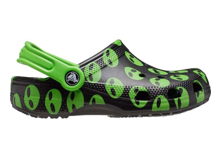 Zuecos Crocs negros con estampado de caras de alienígenas verdes y correa verde.
