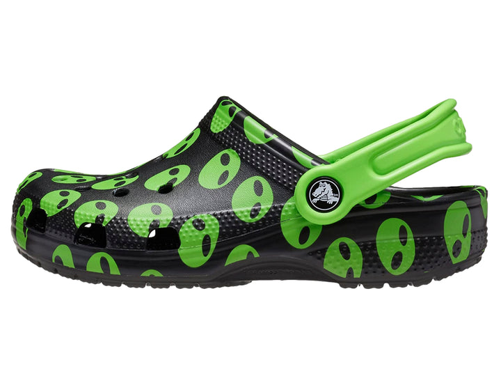 Zuecos Crocs negros con estampado de caras de alienígenas verdes y correa verde.