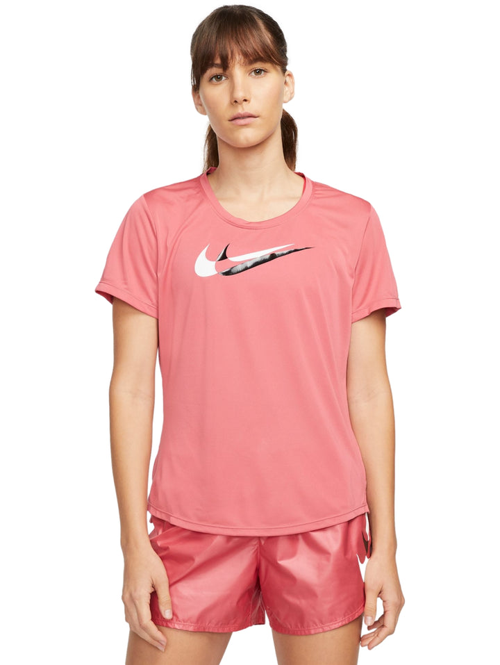 Mujer vistiendo camiseta deportiva Nike de color rosa con logotipo blanco en el pecho y shorts a juego.