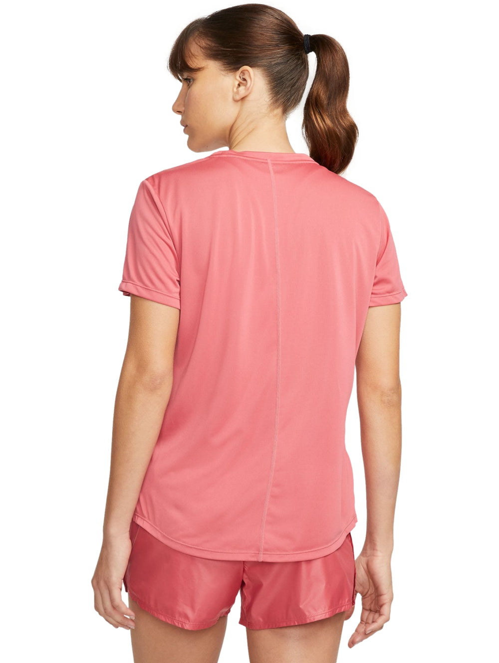Mujer vistiendo camiseta deportiva Nike de color rosa con logotipo blanco en el pecho y shorts a juego.