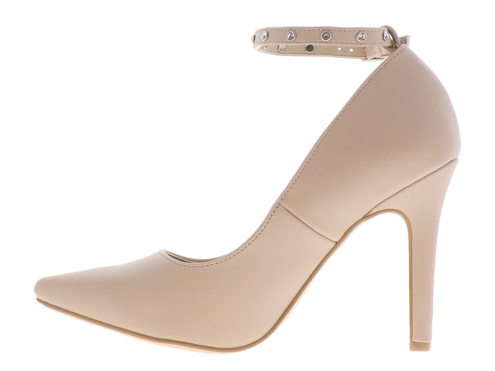 Zapato de tacón alto color beige con punta fina y correa al tobillo con detalles metálicos.
