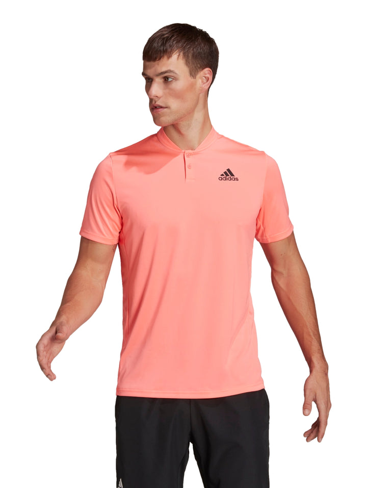 Hombre vistiendo playera deportiva Adidas color rojo ácido con logotipo negro en el pecho.