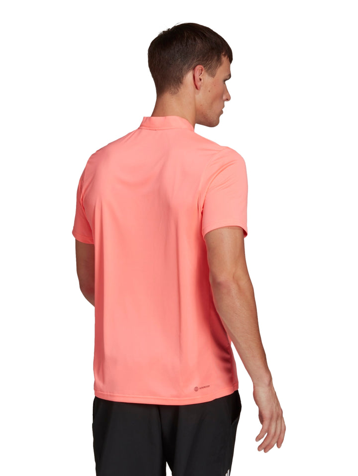 Hombre vistiendo playera deportiva Adidas color rojo ácido con logotipo negro en el pecho.