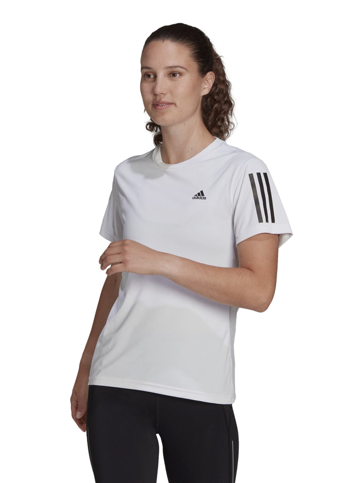 Mujer vistiendo playera deportiva Adidas blanca de manga corta con rayas negras en las mangas.