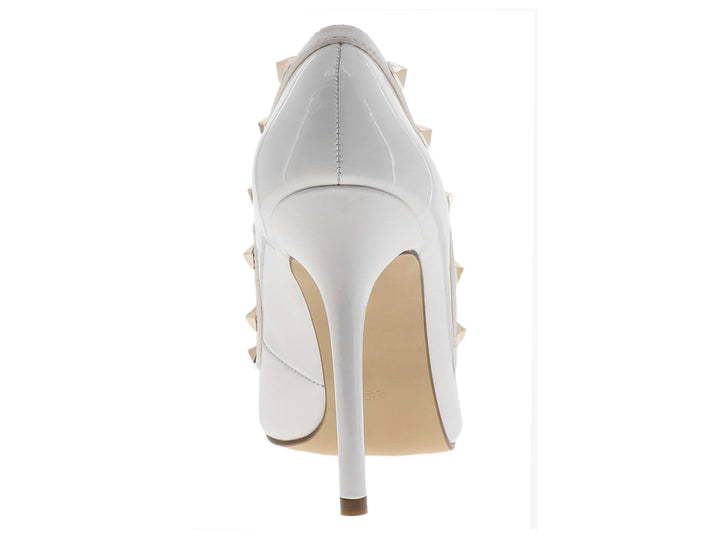 Zapato de tacón alto blanco en acabado charol con detalles de tachuelas doradas.