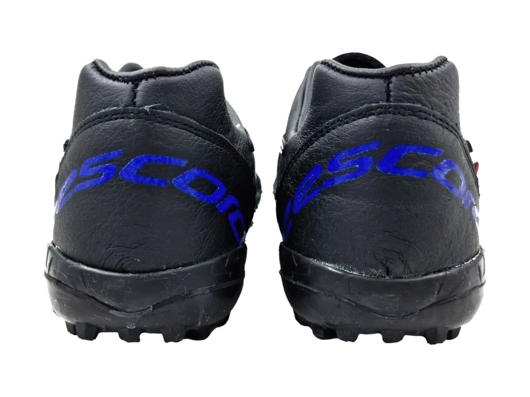 Zapato de fútbol turf color negro con detalles en azul rey y suela de goma con tacos pequeños.