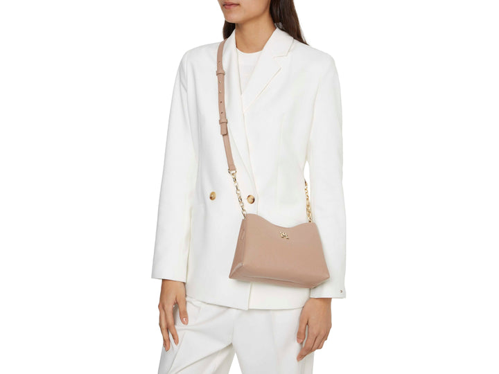 Bolso Tommy Hilfiger color beige con textura graneada, cadena dorada y logo metálico frontal.
