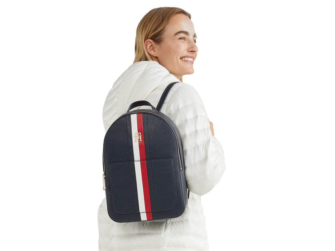 Mujer con mochila azul marino con franja vertical blanca y roja de Tommy Hilfiger.