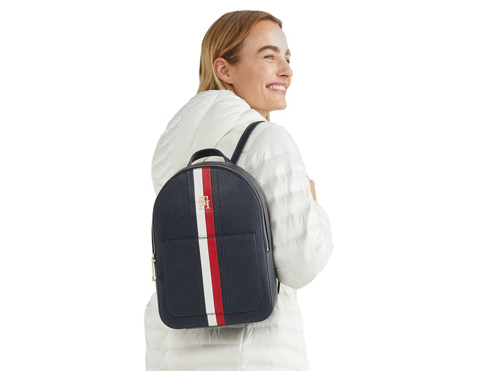 Mujer con mochila azul marino con franja vertical blanca y roja de Tommy Hilfiger.