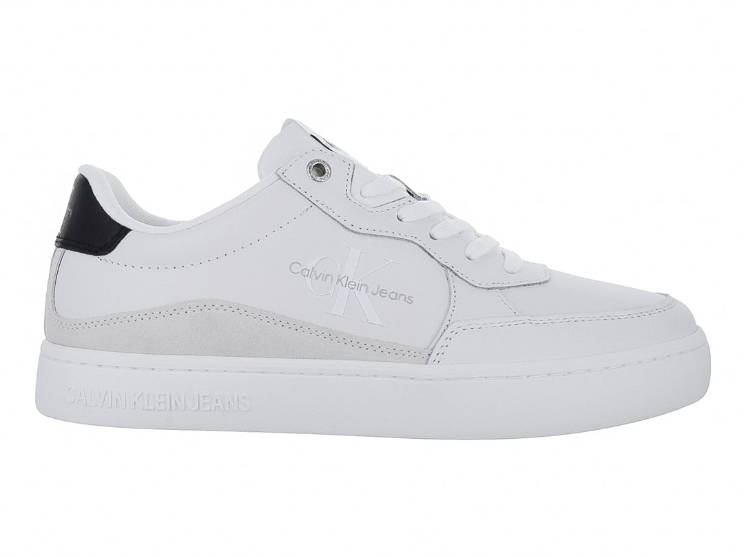 Tenis Calvin Klein blancos de cuero con detalle negro en el talón y suela blanca ancha.