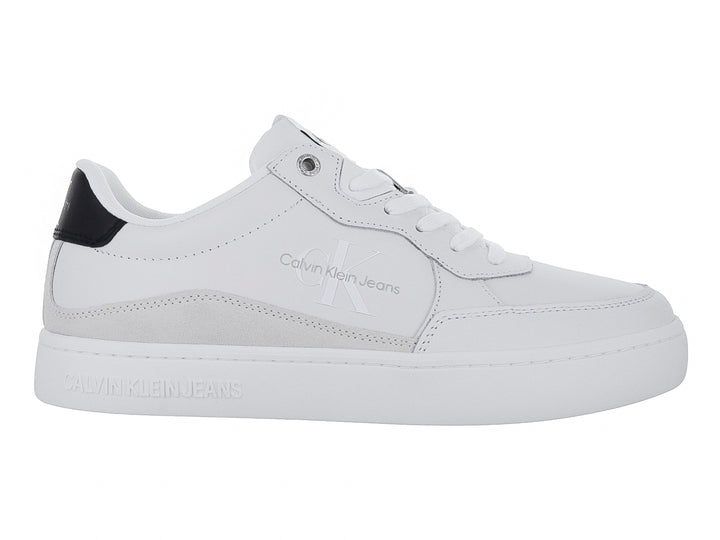 Tenis Calvin Klein blancos de cuero con detalle negro en el talón y suela blanca ancha.