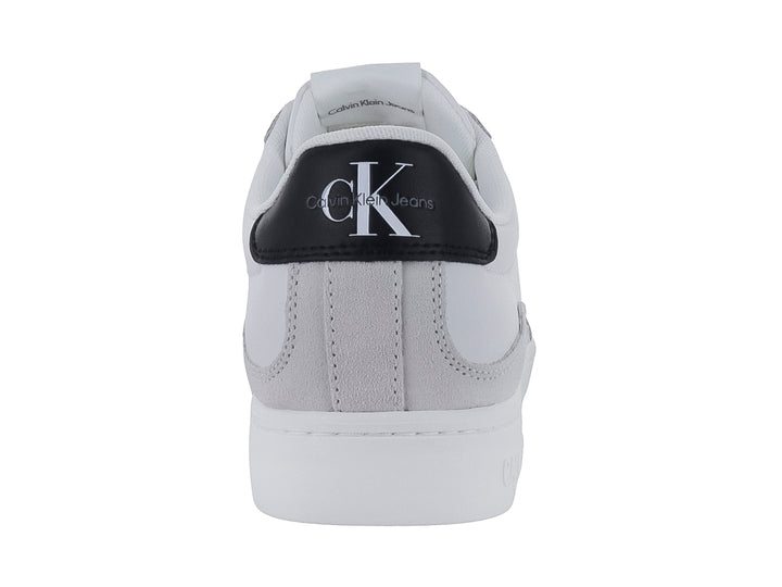 Tenis Calvin Klein blancos de cuero con detalle negro en el talón y suela blanca ancha.