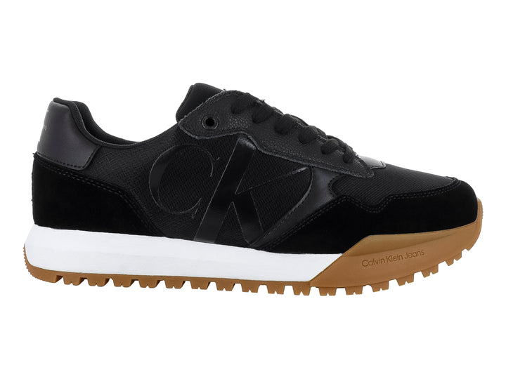 Tenis Calvin Klein negros con suela blanca y café y diseño de suela dentada.