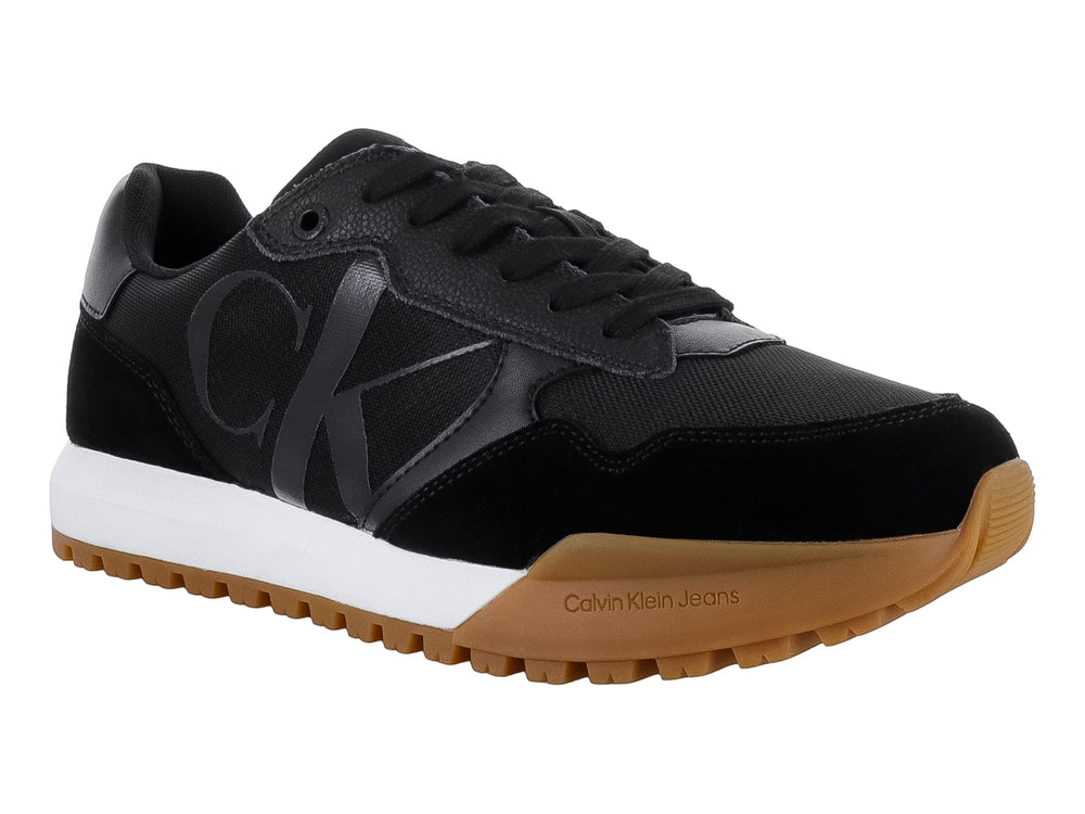 Tenis Calvin Klein negros con suela blanca y café y diseño de suela dentada.