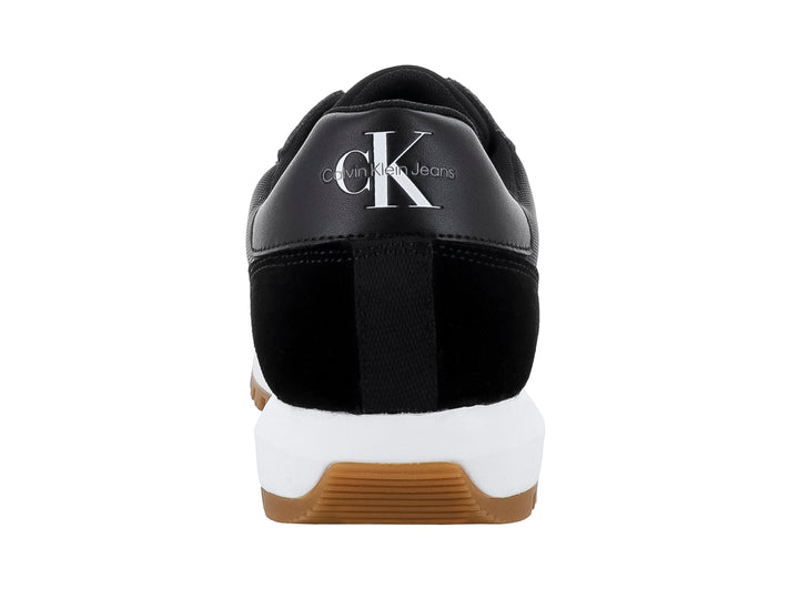 Tenis Calvin Klein negros con suela blanca y café y diseño de suela dentada.
