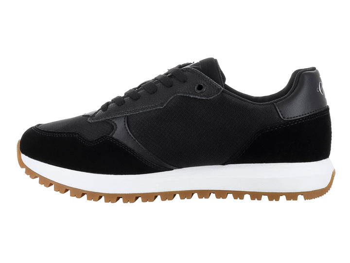 Tenis Calvin Klein negros con suela blanca y café y diseño de suela dentada.