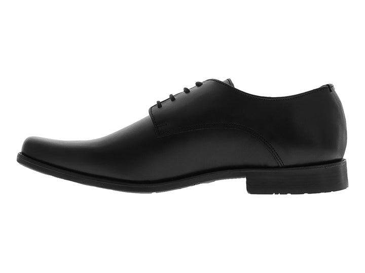 Zapato formal negro de material sintético con cordones y suela plana para niño.