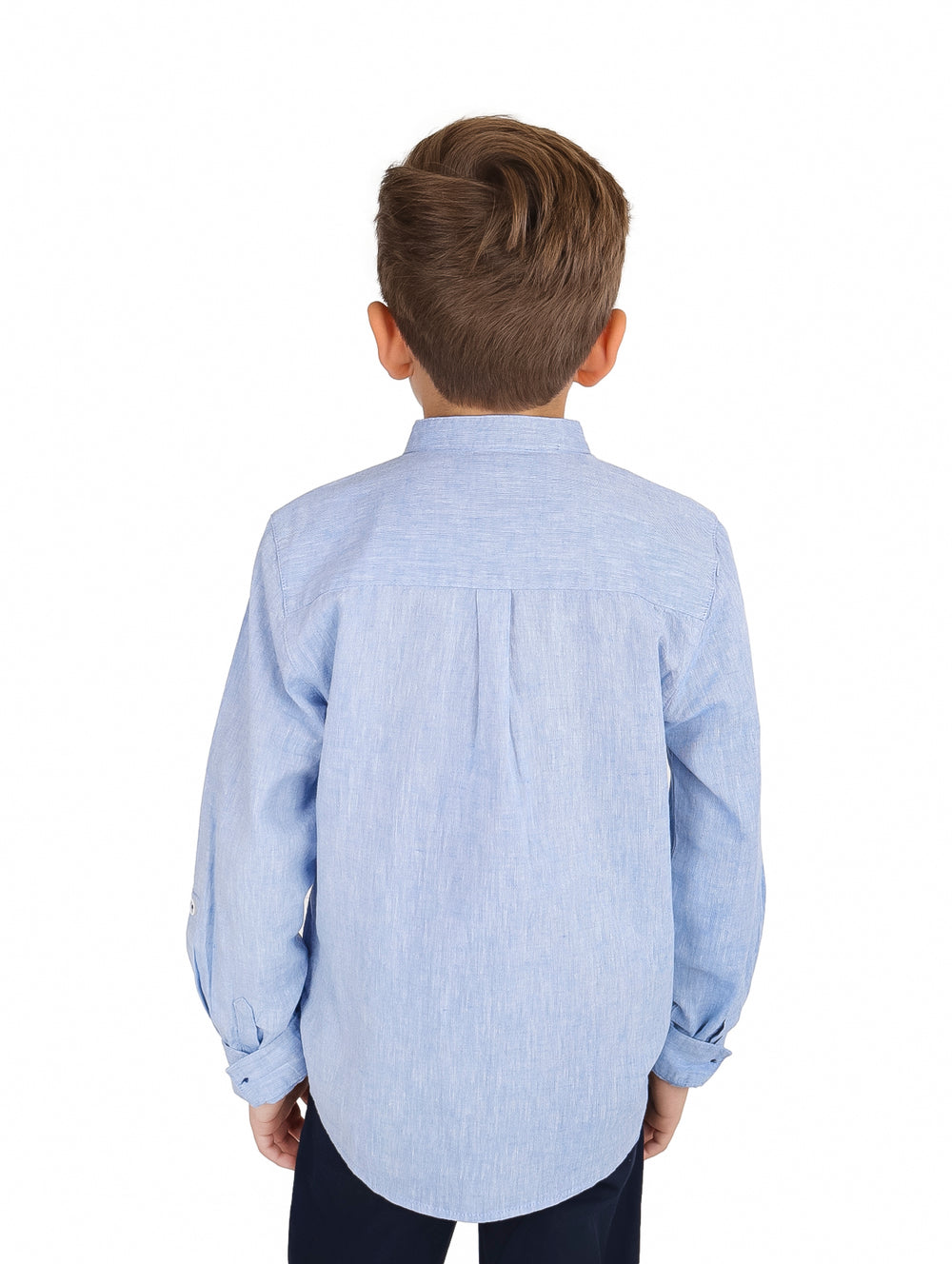 Niño vistiendo camisa de manga larga color azul claro con cuello mao y bolsillo frontal.
