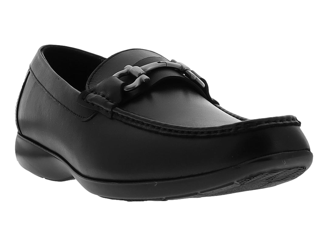 Zapato tipo mocasín color negro con hebilla metálica plateada sobre fondo blanco.