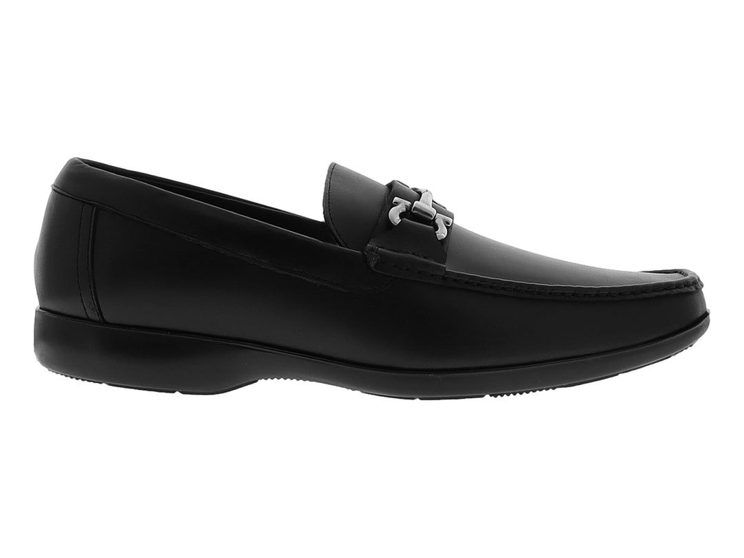 Zapato tipo mocasín color negro con detalle metálico plateado en la parte superior y suela plana.