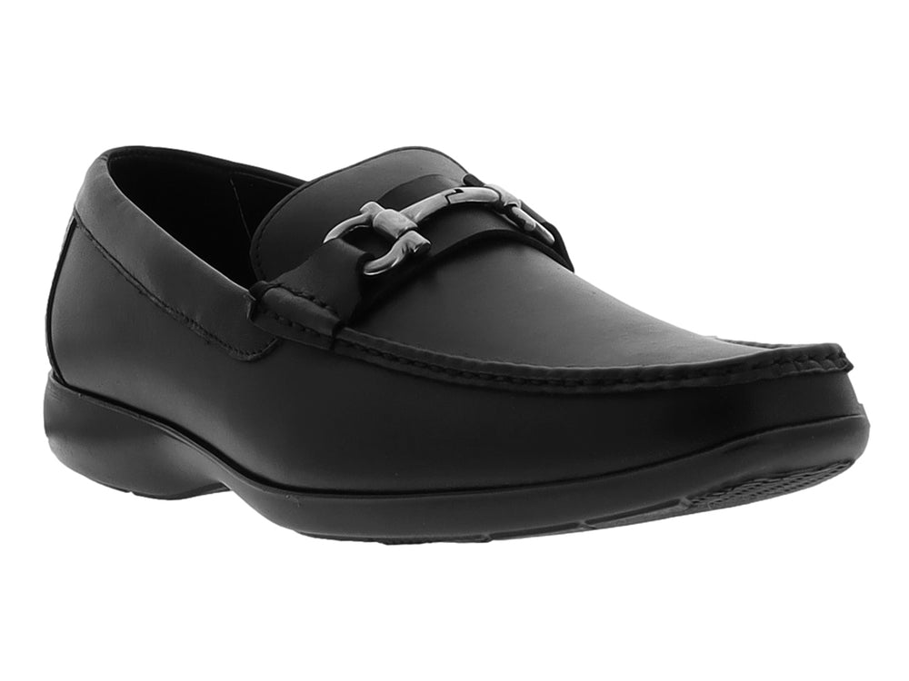 Zapato tipo mocasín color negro con detalle metálico plateado en la parte superior y suela plana.