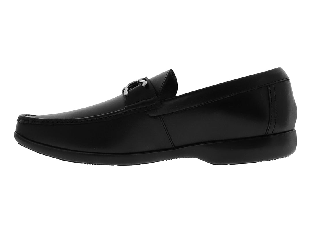Zapato tipo mocasín color negro con detalle metálico plateado en la parte superior y suela plana.