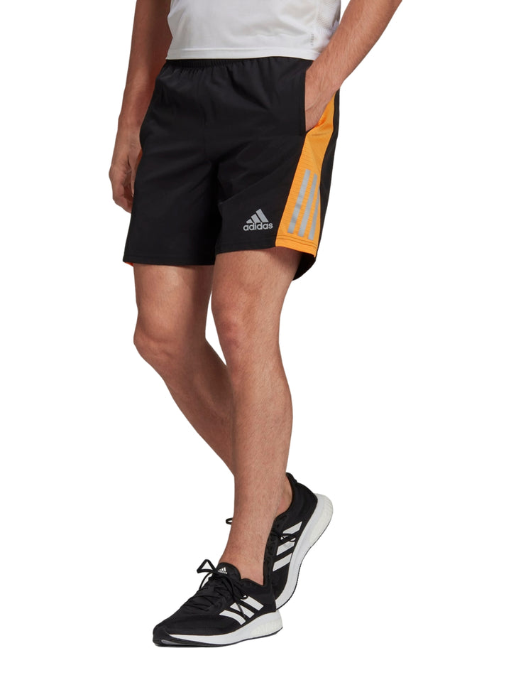Pantalones cortos deportivos Adidas color negro con detalles laterales en naranja y franjas reflectantes.