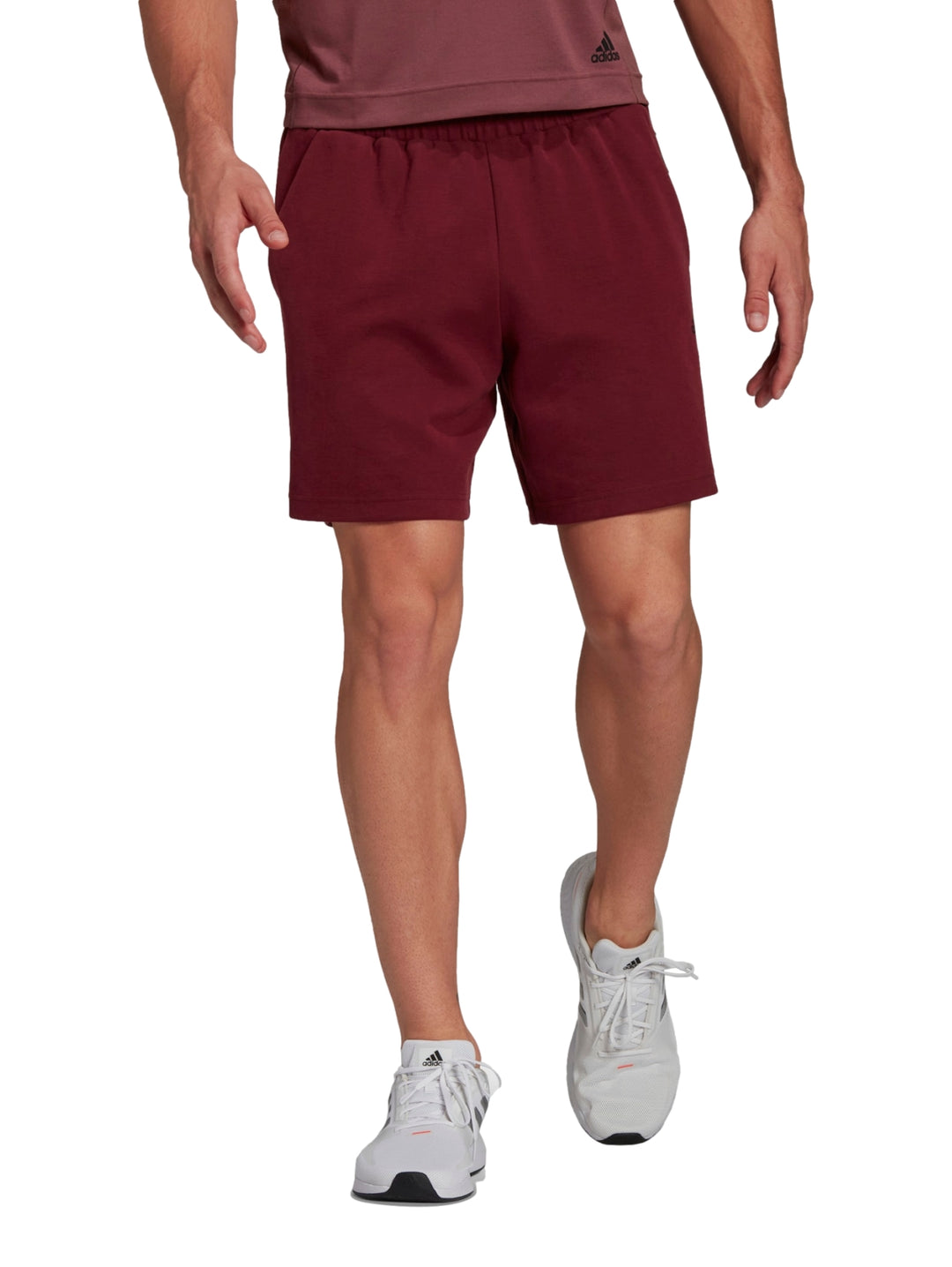 Hombre usando shorts deportivos Adidas en color rojo oscuro.