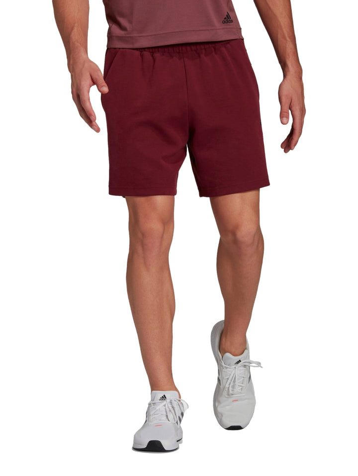 Hombre usando shorts deportivos Adidas en color rojo oscuro.