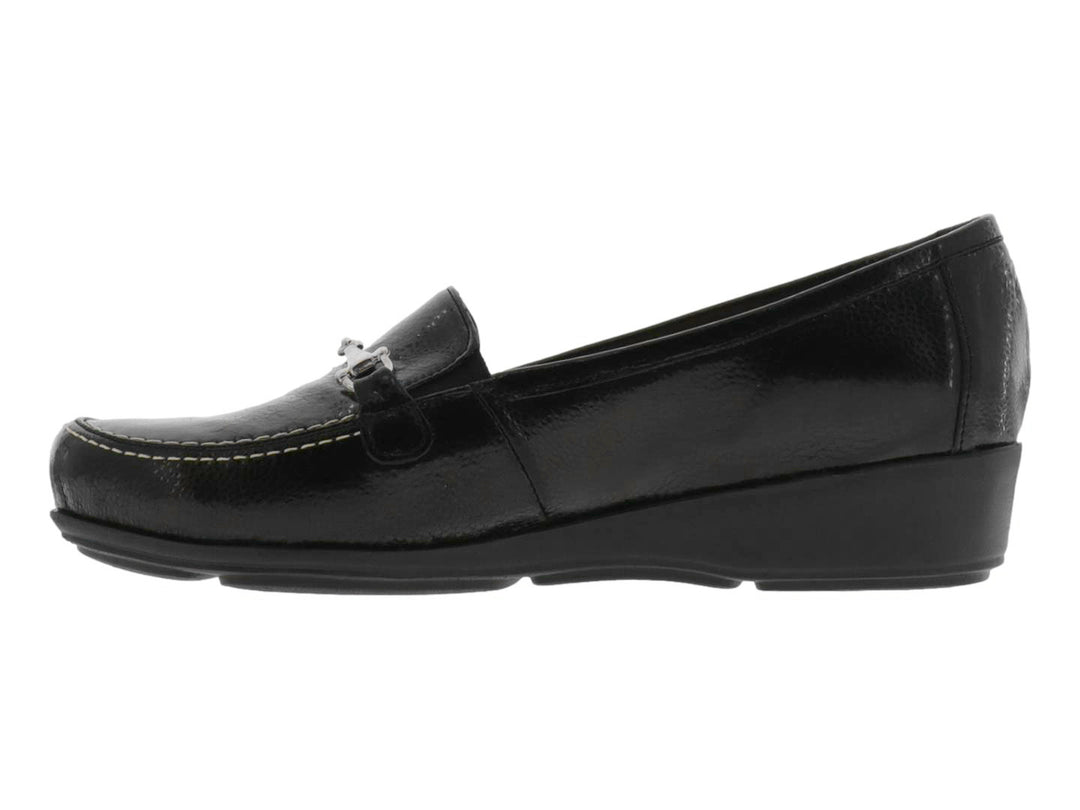 Zapato tipo mocasín color negro brillante con adorno metálico plateado en la parte superior.