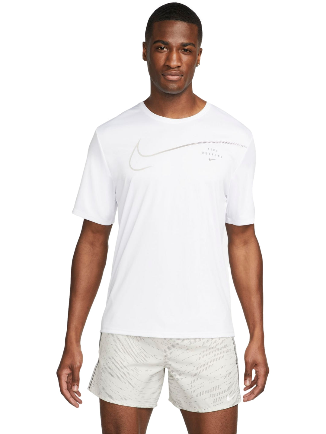 Hombre vistiendo camiseta deportiva Nike blanca de manga corta y shorts color beige.