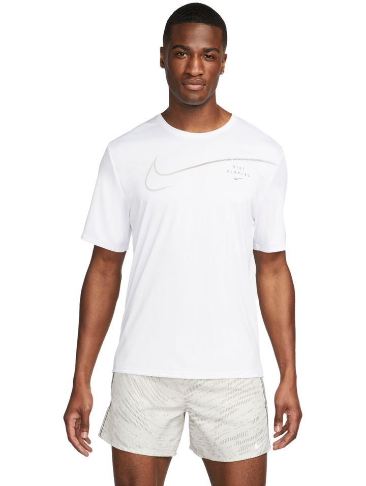 Hombre vistiendo camiseta deportiva Nike blanca de manga corta y shorts color beige.