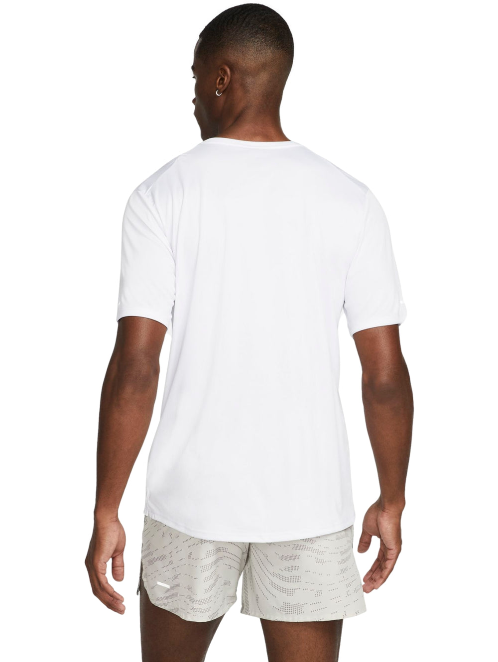 Hombre vistiendo camiseta deportiva Nike blanca de manga corta y shorts color beige.