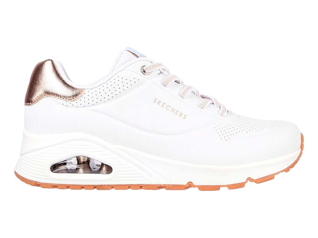 Tenis deportivos Skechers blancos con detalles dorados en el talón y suela blanca con cámara de aire.