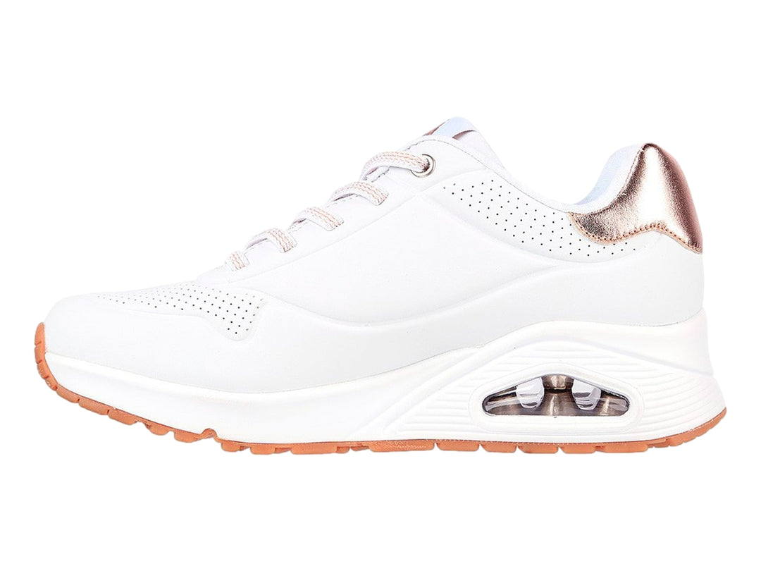 Tenis deportivos Skechers blancos con detalles dorados en el talón y suela blanca con cámara de aire.