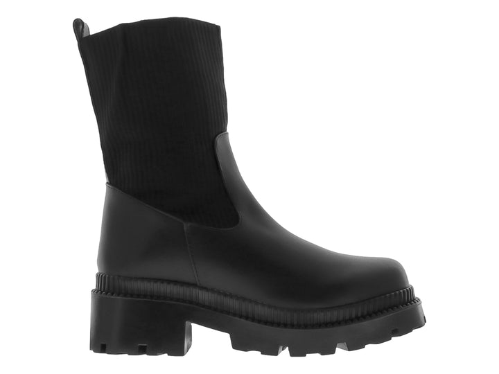 Bota negra de caña elástica y suela track gruesa sobre fondo blanco.
