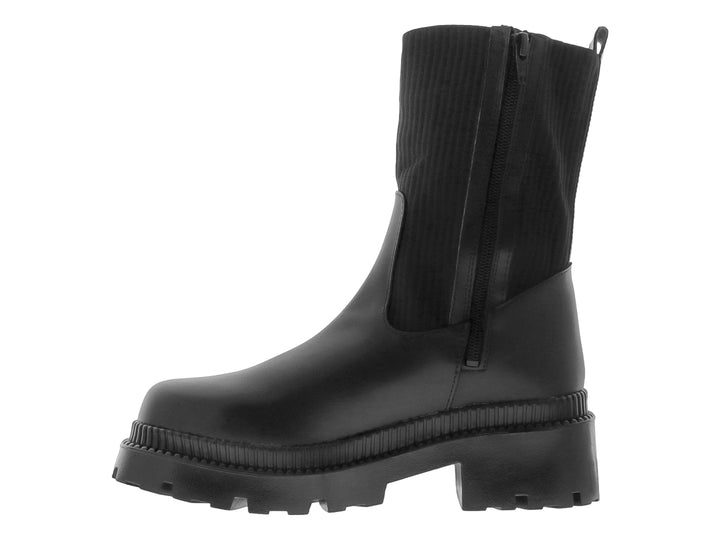 Bota negra de caña elástica y suela track gruesa sobre fondo blanco.
