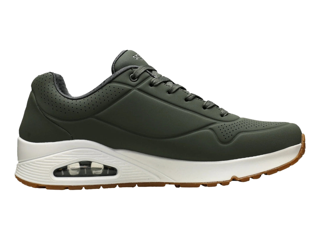 Tenis Skechers color verde oliva con suela blanca y amortiguación visible en el talón.