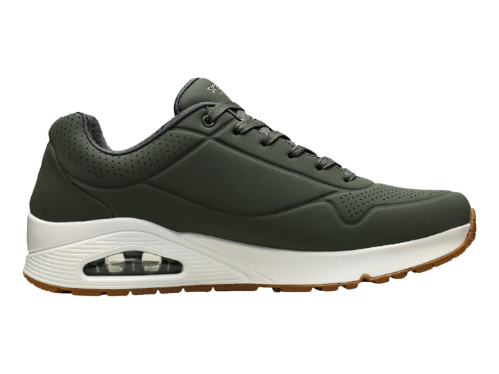 Tenis Skechers color verde oliva con suela blanca y amortiguación visible en el talón.