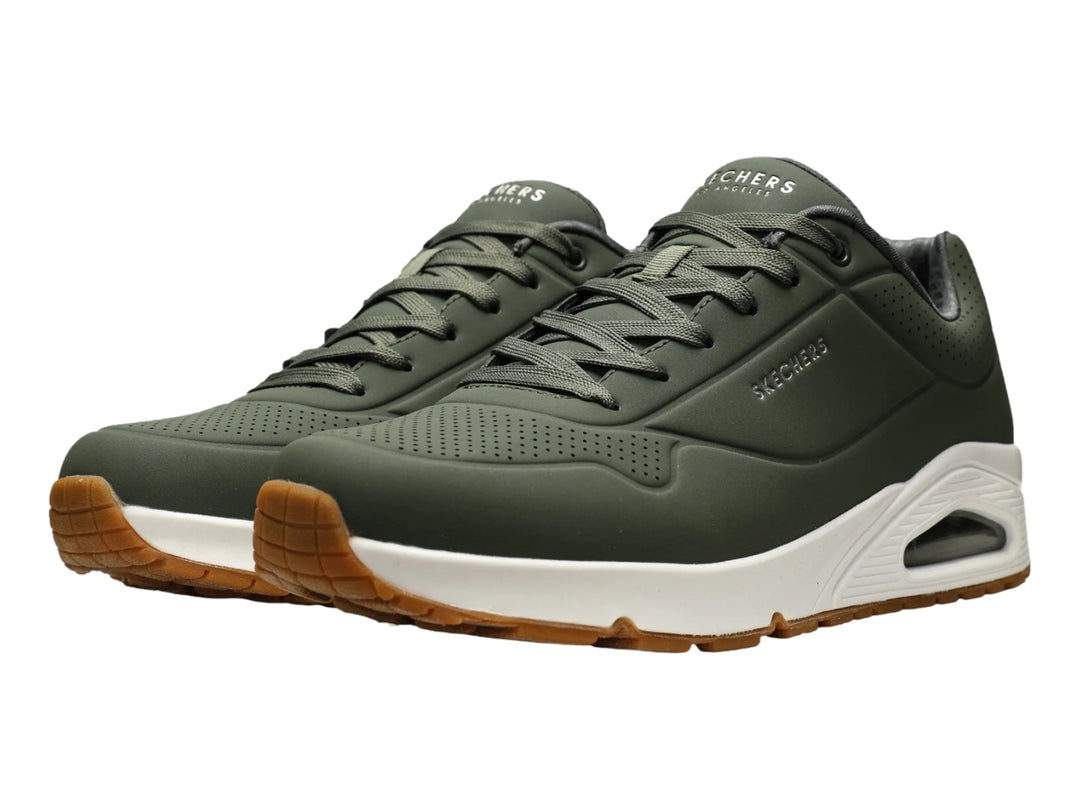 Tenis Skechers color verde oliva con suela blanca y amortiguación visible en el talón.