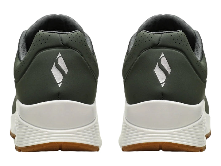 Tenis Skechers color verde oliva con suela blanca y amortiguación visible en el talón.