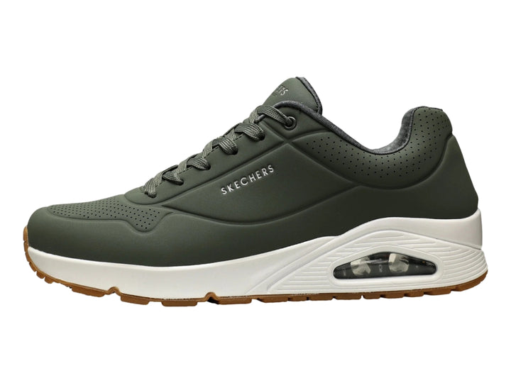 Tenis Skechers color verde oliva con suela blanca y amortiguación visible en el talón.