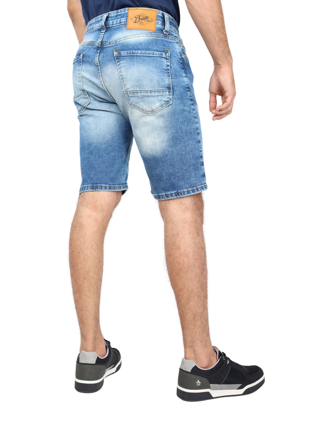 Hombre vistiendo bermudas de mezclilla color stone y tenis negros.
