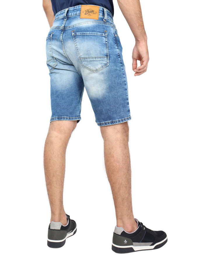 Hombre vistiendo bermudas de mezclilla color stone y tenis negros.