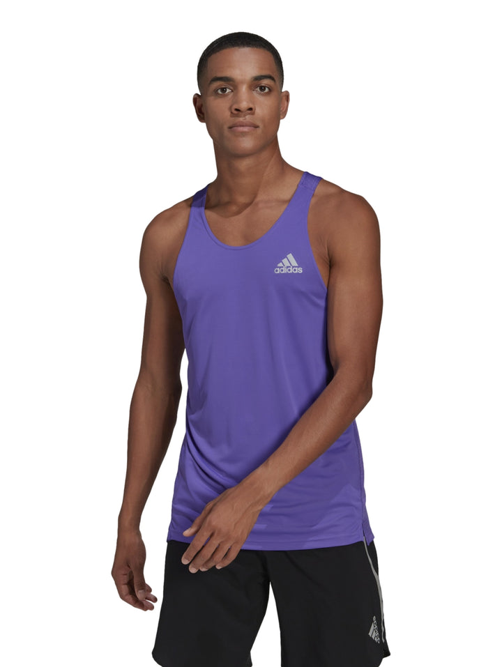 Hombre vistiendo camiseta deportiva sin mangas color morado de la marca Adidas con logo reflectante en el pecho.